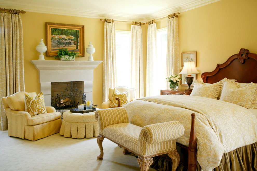 Exempel på ett klassiskt sovrum, med gula väggar, heltäckningsmatta och en standard öppen spis