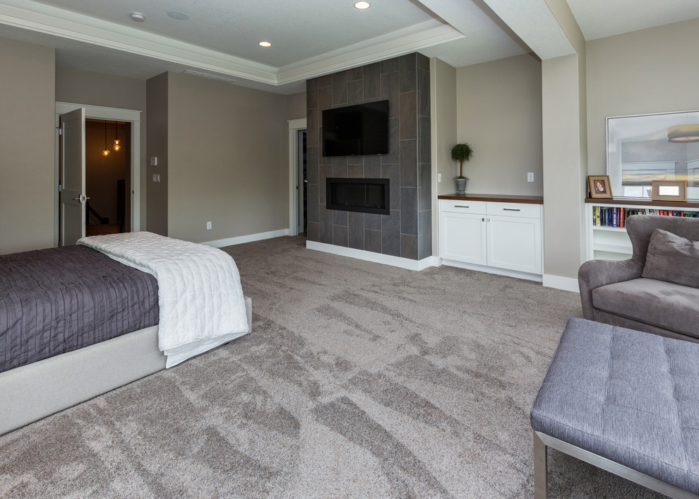 На фото: большая хозяйская спальня в стиле неоклассика (современная классика) с серыми стенами, ковровым покрытием, горизонтальным камином и фасадом камина из плитки с