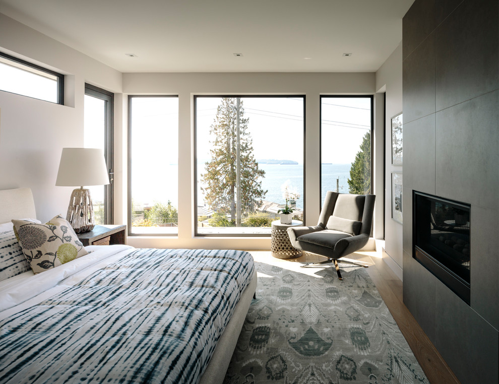 Großes Modernes Hauptschlafzimmer mit weißer Wandfarbe, braunem Holzboden, Tunnelkamin und gefliester Kaminumrandung in Vancouver