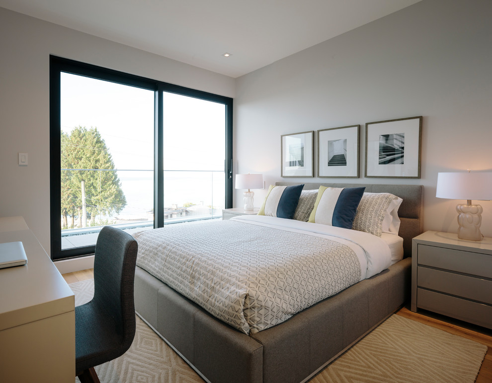 Diseño de habitación de invitados actual grande con paredes grises y suelo de madera en tonos medios
