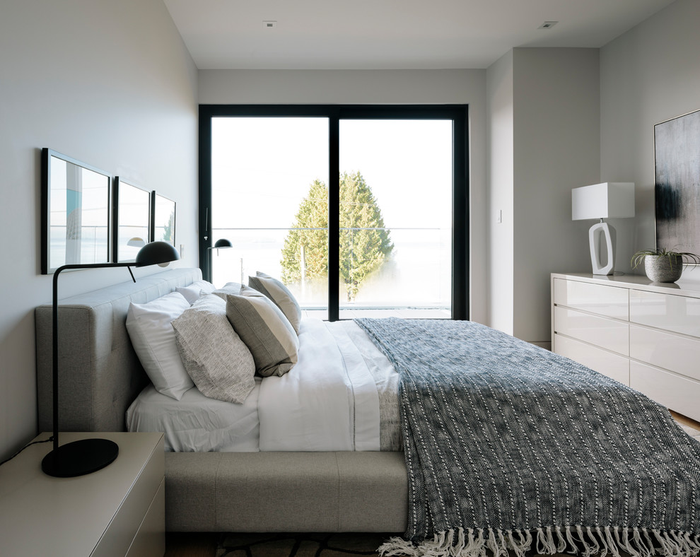 Modelo de habitación de invitados actual grande con paredes grises y suelo de madera en tonos medios
