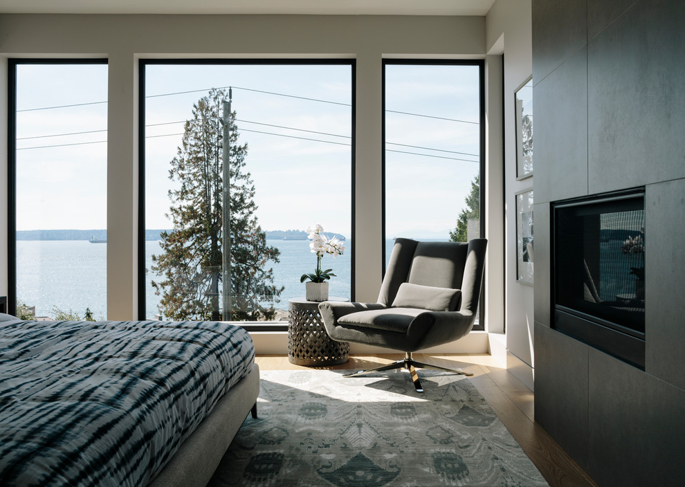 Example of a large trendy master medium tone wood floor bedroom design in Vancouver with white walls, a two-sided fireplace and a tile fireplace