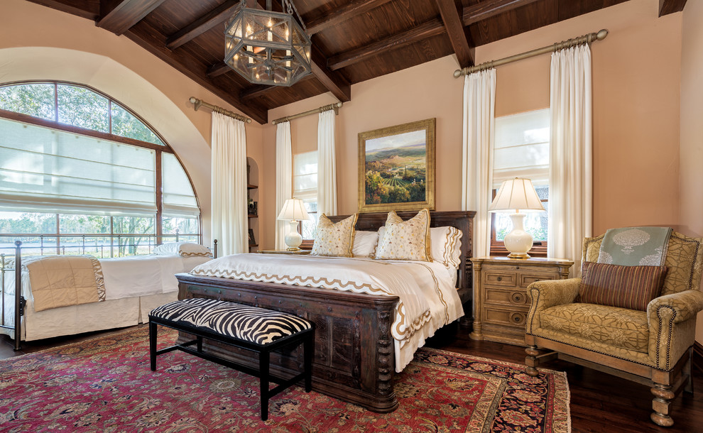 Inspiration for a mediterranean master bedroom in Tampa with beige walls and dark hardwood flooring.