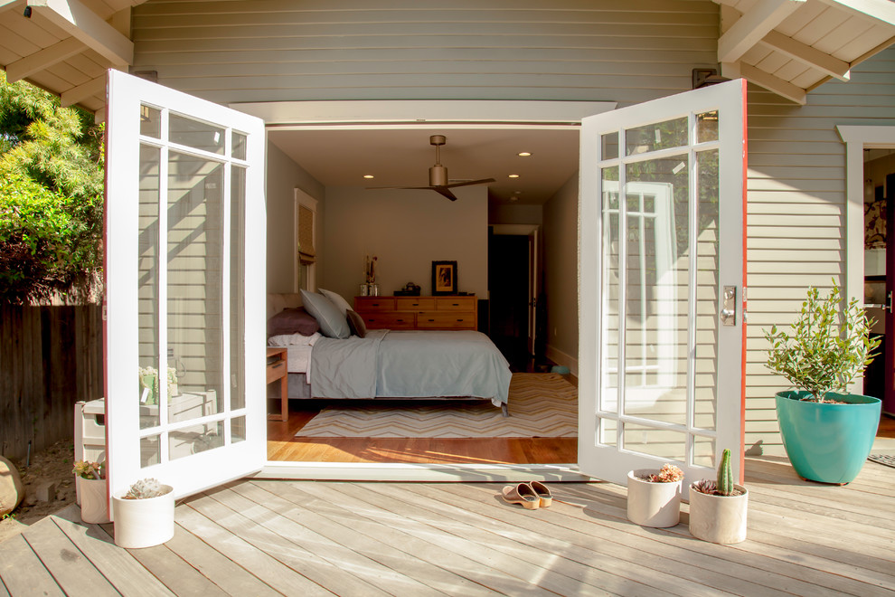 Modelo de dormitorio principal de estilo americano pequeño con paredes grises y suelo de madera en tonos medios