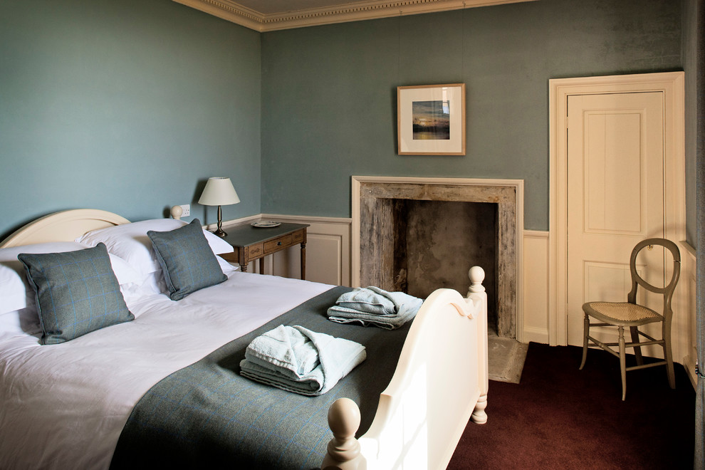Ejemplo de habitación de invitados clásica pequeña con paredes azules, moqueta, todas las chimeneas y marco de chimenea de piedra
