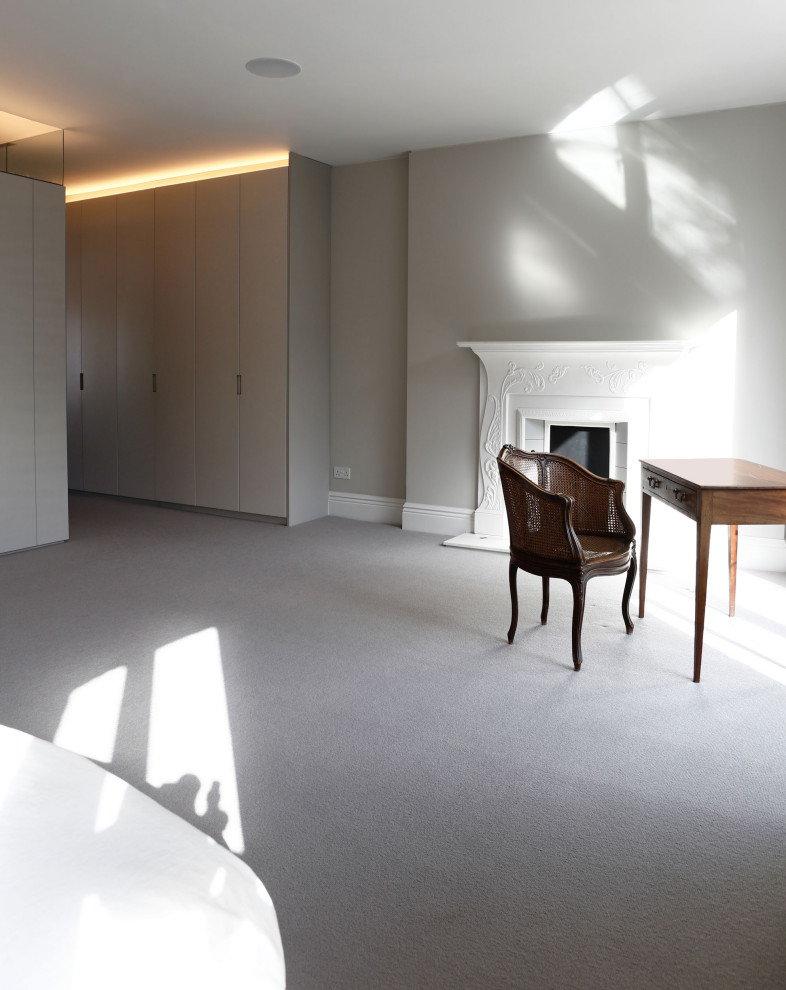 Idée de décoration pour une grande chambre design avec une cheminée standard, un manteau de cheminée en plâtre et un sol gris.