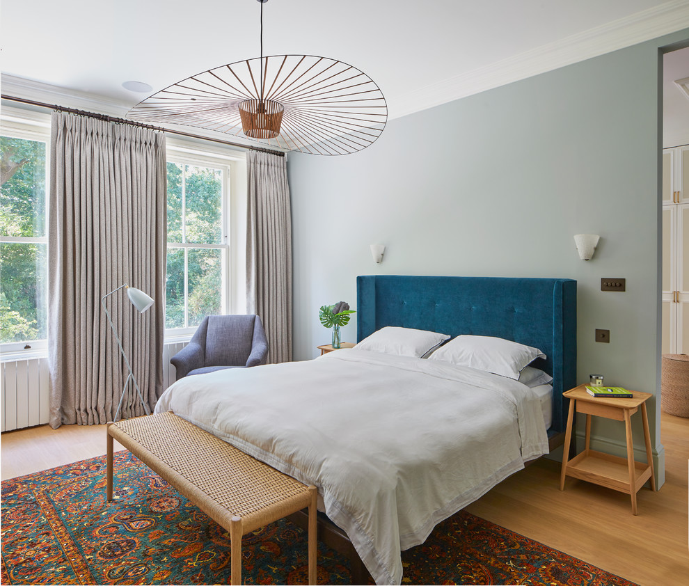 Inspiration for a contemporary bedroom in London with blue walls, medium hardwood flooring and brown floors.