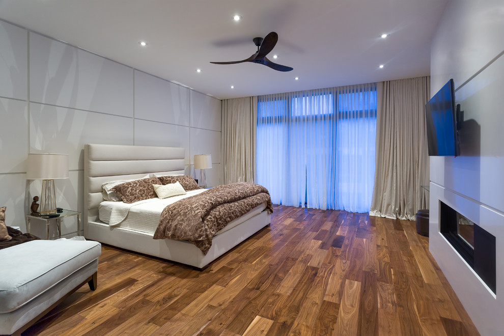 Diseño de dormitorio tradicional renovado con paredes blancas, suelo de madera en tonos medios y todas las chimeneas