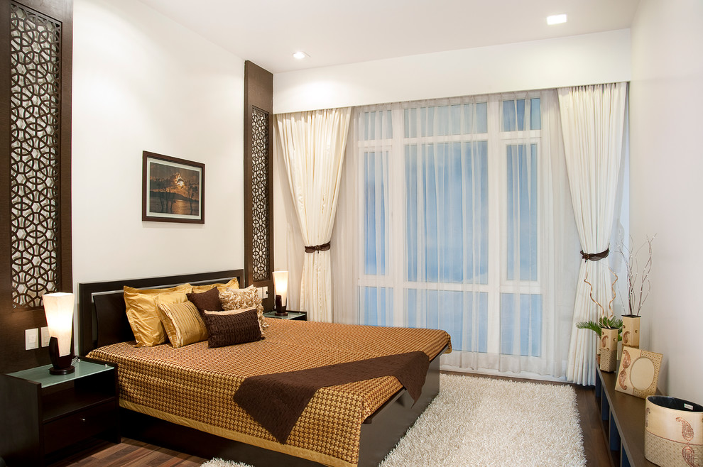 Kleines Modernes Gästezimmer mit beiger Wandfarbe und dunklem Holzboden in Kalkutta