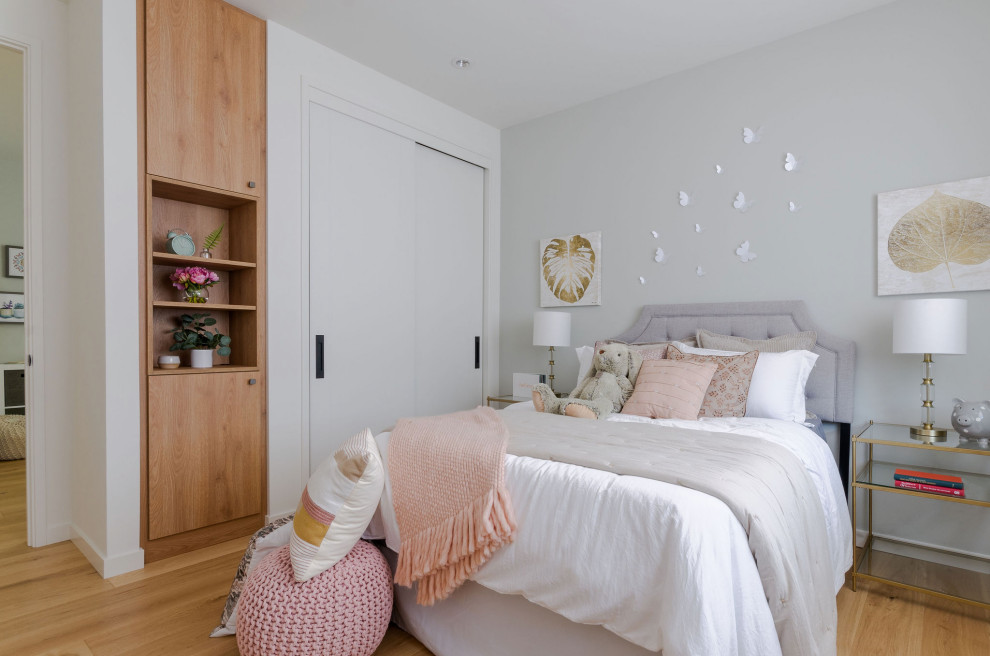 Modelo de dormitorio clásico renovado de tamaño medio con paredes grises, suelo de madera en tonos medios y suelo marrón