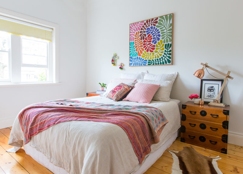 This is an example of a large bohemian guest bedroom in Melbourne with white walls and light hardwood flooring.