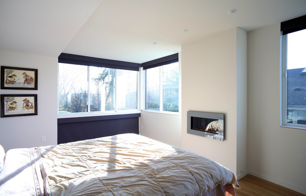 Inspiration pour une grande chambre parentale minimaliste avec un mur blanc, parquet en bambou, un manteau de cheminée en plâtre et une cheminée standard.
