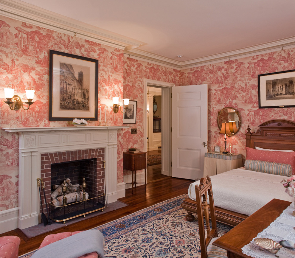 Foto di una camera da letto chic con cornice del camino in mattoni, pareti rosa e camino classico