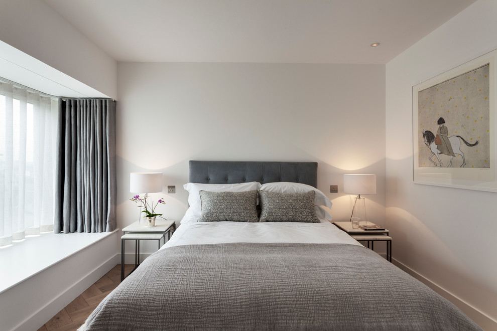 Immagine di una camera degli ospiti moderna di medie dimensioni con pareti bianche, pavimento in legno massello medio e pavimento beige