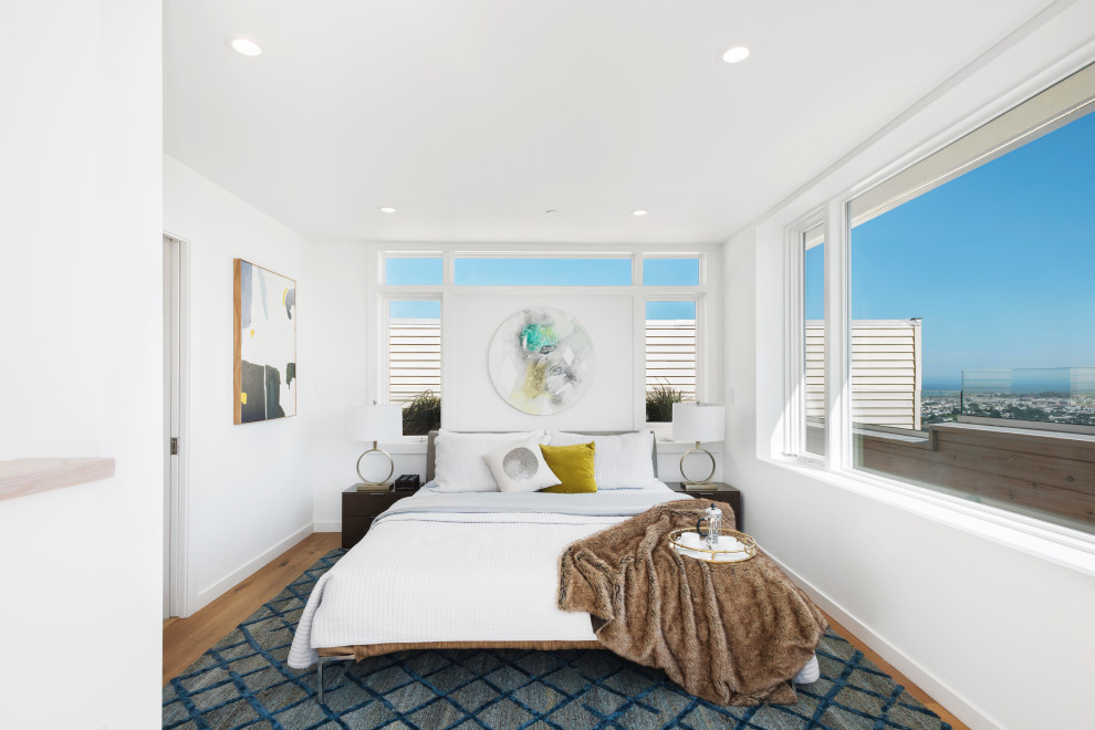 Design ideas for a contemporary bedroom in San Francisco with white walls, medium hardwood flooring and brown floors.