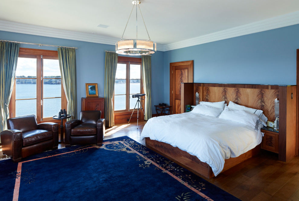 Aménagement d'une chambre d'amis victorienne de taille moyenne avec un mur bleu, parquet foncé, aucune cheminée et un sol marron.