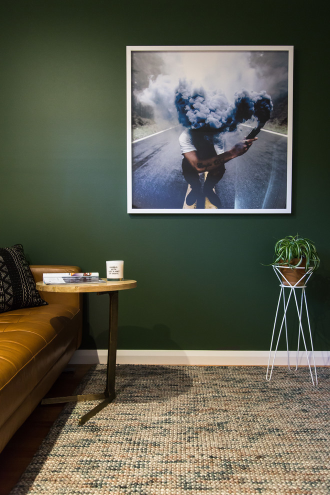 Réalisation d'une chambre d'amis minimaliste avec un mur vert, un sol en bois brun et un sol marron.