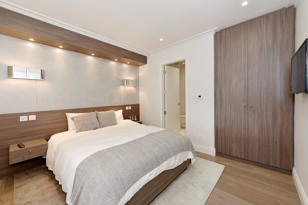 Diseño de dormitorio actual con paredes grises, suelo de madera clara y suelo beige