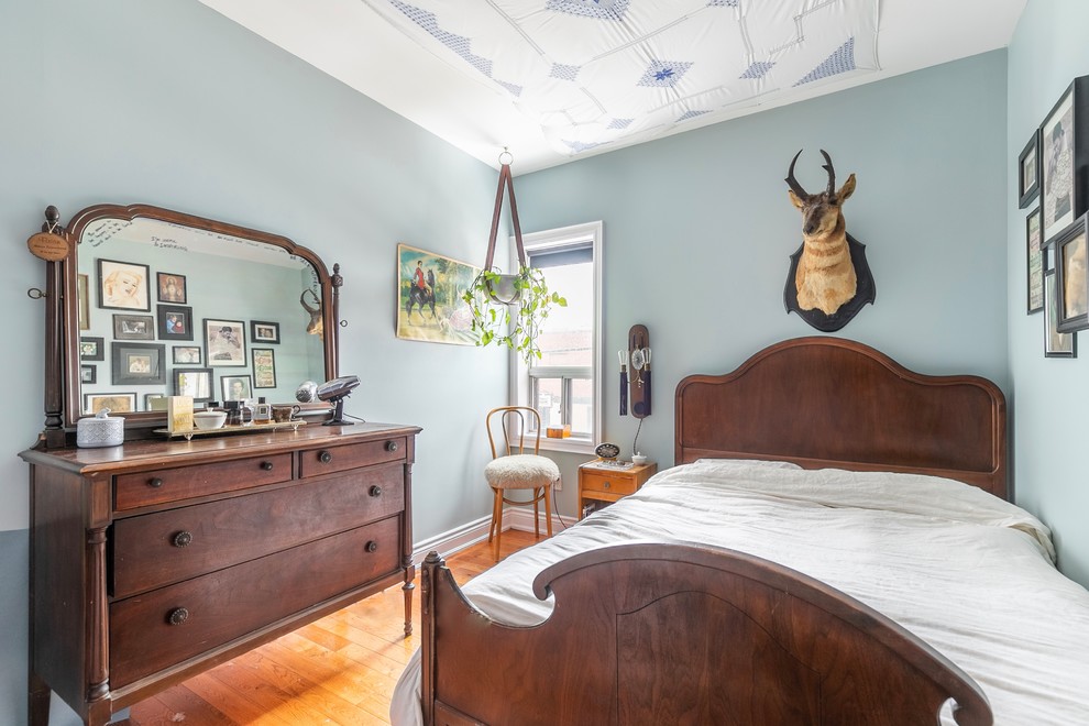 Kleines Stilmix Hauptschlafzimmer mit blauer Wandfarbe und braunem Holzboden in Toronto