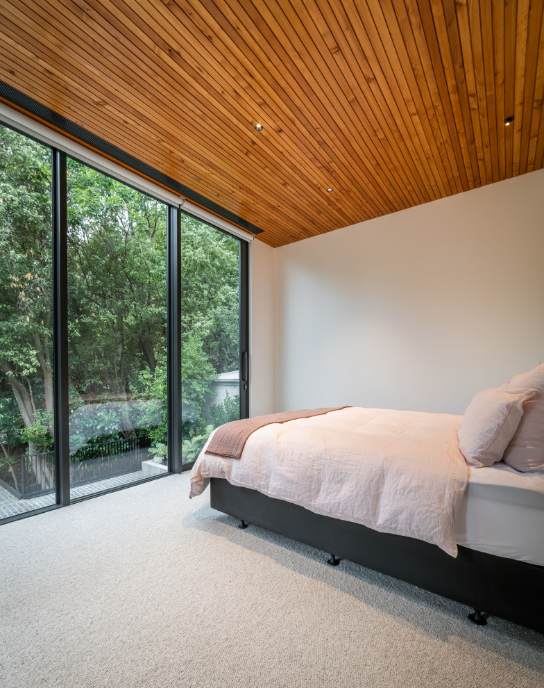 Cette photo montre une chambre avec moquette moderne avec un mur beige, un sol beige et un plafond en bois.
