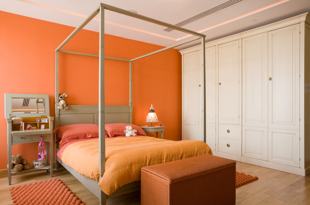 Imagen de dormitorio campestre con parades naranjas y suelo de madera clara