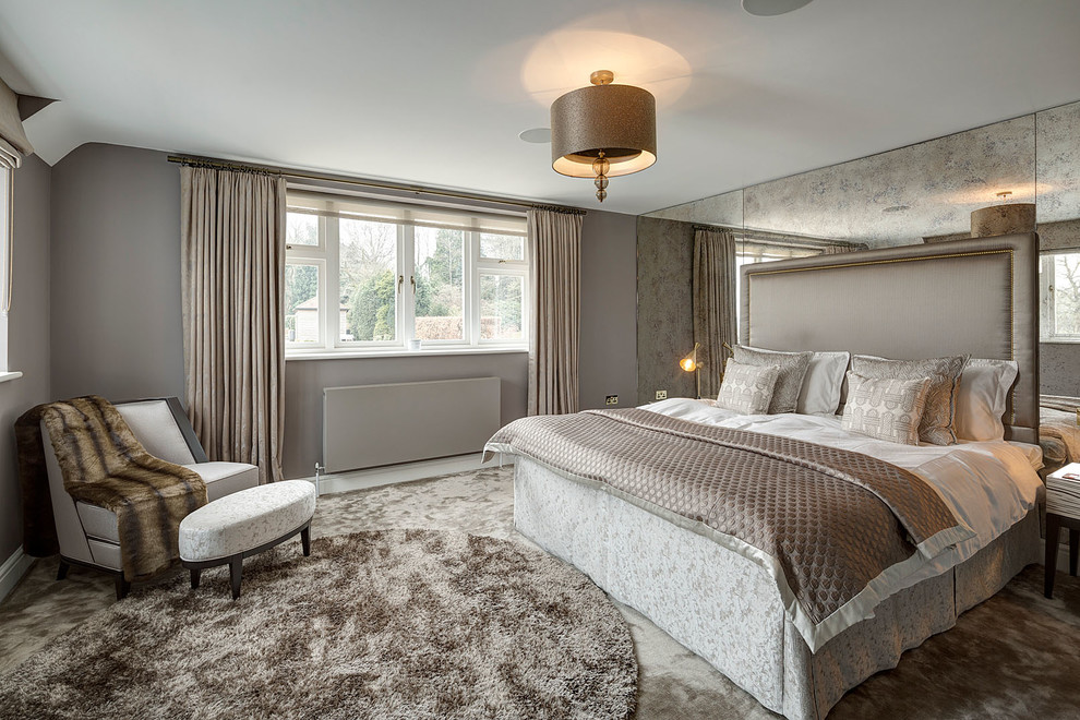Large contemporary master bedroom in Surrey with carpet.