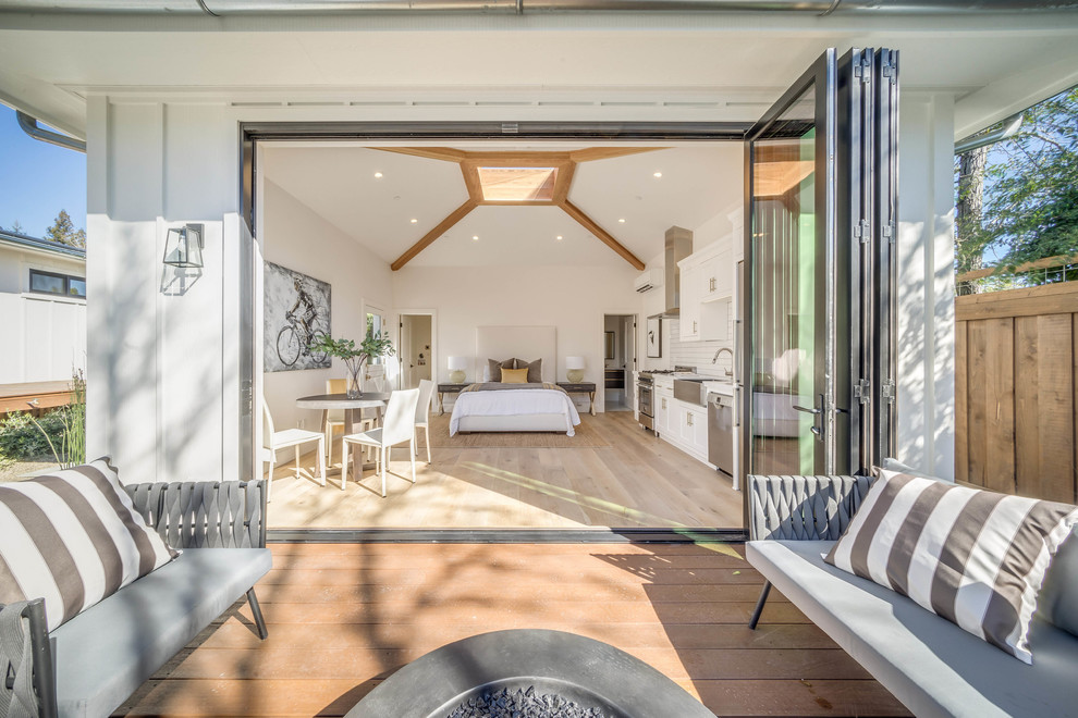 Diseño de habitación de invitados de estilo de casa de campo grande con paredes blancas y suelo de madera clara