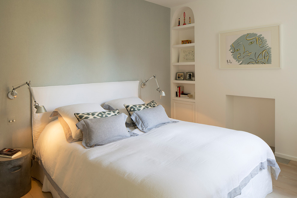 Modelo de dormitorio principal actual de tamaño medio con paredes blancas, suelo de madera clara y suelo beige