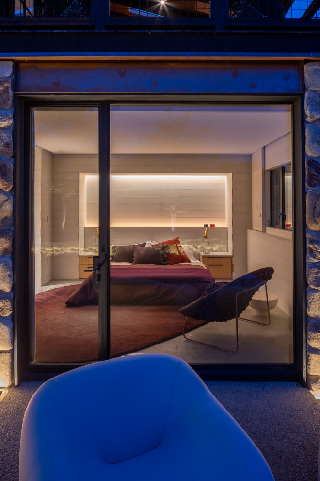 Immagine di una camera degli ospiti moderna di medie dimensioni con pareti beige, pavimento in cemento, pavimento grigio e pareti in legno