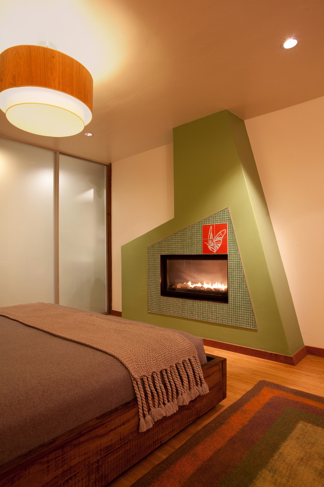На фото: большая хозяйская спальня в стиле модернизм с белыми стенами, полом из бамбука, стандартным камином и фасадом камина из плитки с