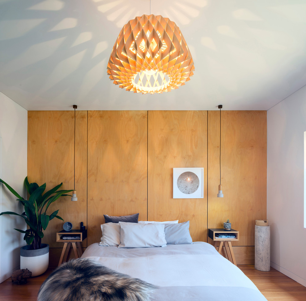 Idées déco pour une chambre parentale moderne avec un mur blanc, un sol en bois brun et un sol beige.