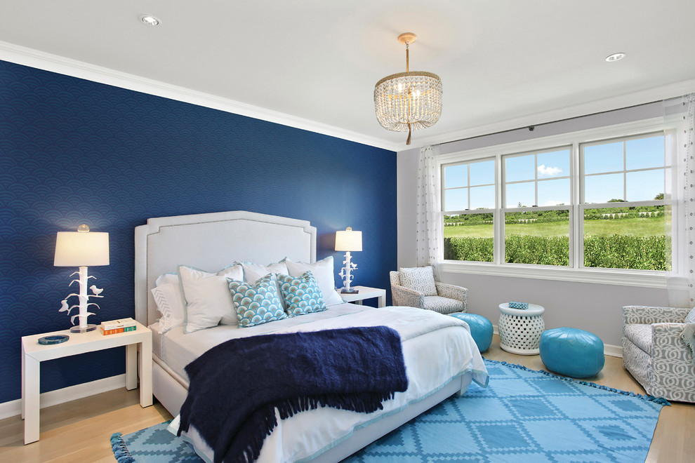 ニューヨークにある広いビーチスタイルのおしゃれな主寝室 (青い壁、淡色無垢フローリング)