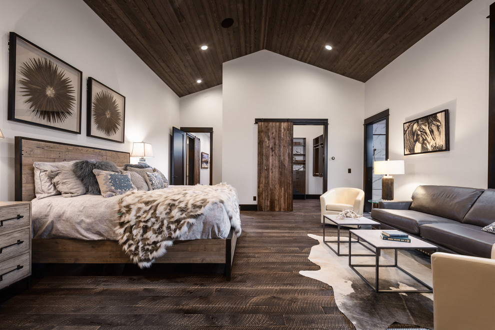 Uriges Schlafzimmer mit weißer Wandfarbe, dunklem Holzboden und braunem Boden in Sonstige