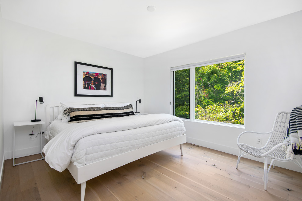 Diseño de habitación de invitados minimalista con paredes blancas, suelo de madera clara y suelo beige