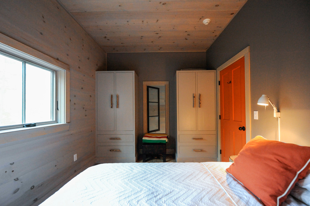 Modelo de dormitorio principal moderno pequeño con paredes grises y suelo de madera en tonos medios