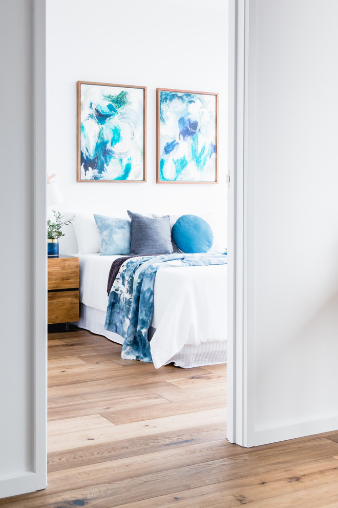 Foto de dormitorio principal contemporáneo de tamaño medio con paredes blancas, suelo de madera clara y suelo marrón