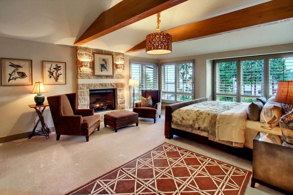 Diseño de dormitorio principal de estilo americano grande con paredes grises, moqueta, todas las chimeneas, marco de chimenea de piedra y suelo gris