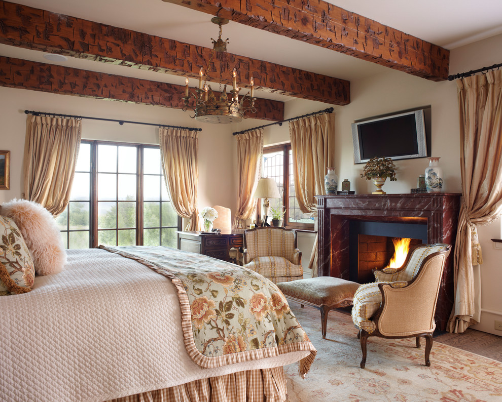 Foto di una camera da letto country con pareti beige, parquet scuro e camino classico