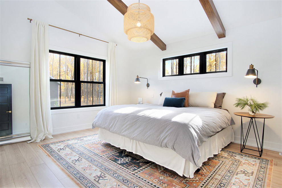 Large scandinavian master bedroom in Grand Rapids with white walls, light hardwood flooring, no fireplace and beige floors.