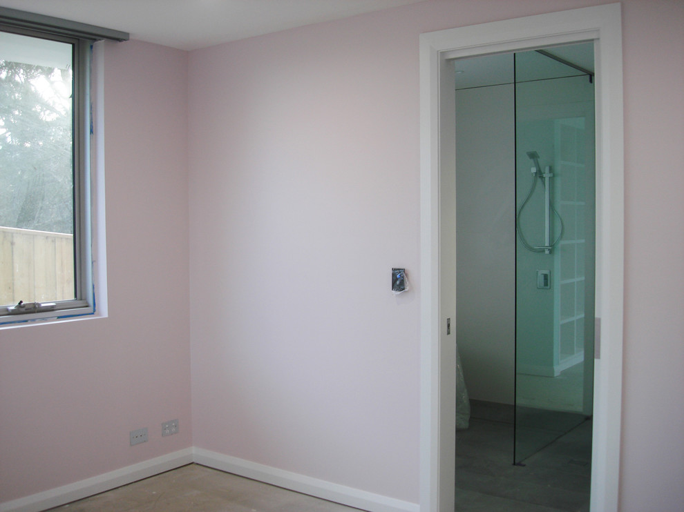 Пример оригинального дизайна: большая гостевая спальня (комната для гостей) в стиле модернизм с полом из фанеры и розовыми стенами
