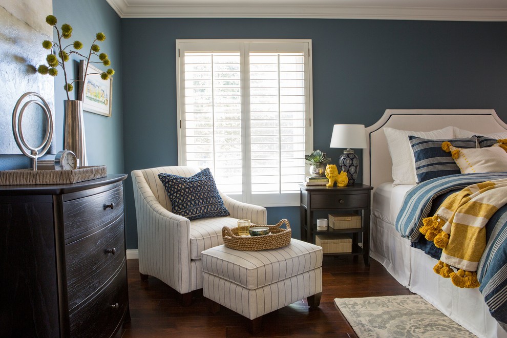 Cette image montre une chambre parentale traditionnelle de taille moyenne avec un mur bleu, parquet foncé, aucune cheminée et un sol marron.
