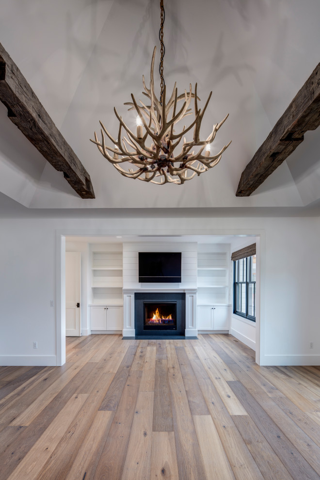 Cette image montre une très grande chambre parentale design avec un mur blanc, un sol en bois brun, une cheminée standard, un manteau de cheminée en pierre et un sol marron.