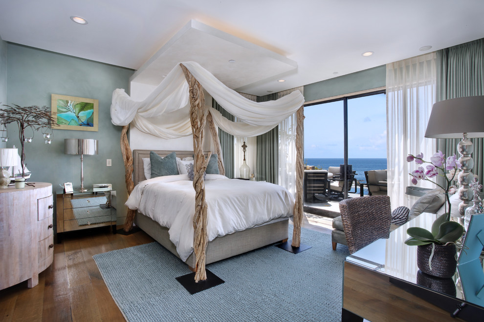 Immagine di una camera da letto contemporanea con pareti blu e pavimento in legno massello medio