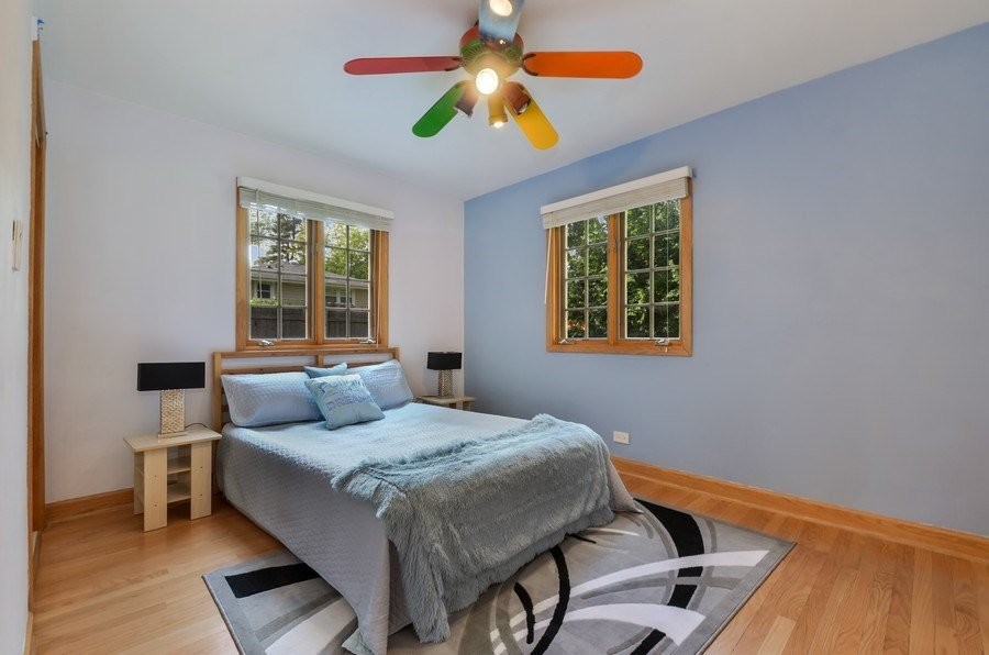 This is an example of a medium sized modern guest bedroom in Chicago with blue walls, medium hardwood flooring and brown floors.