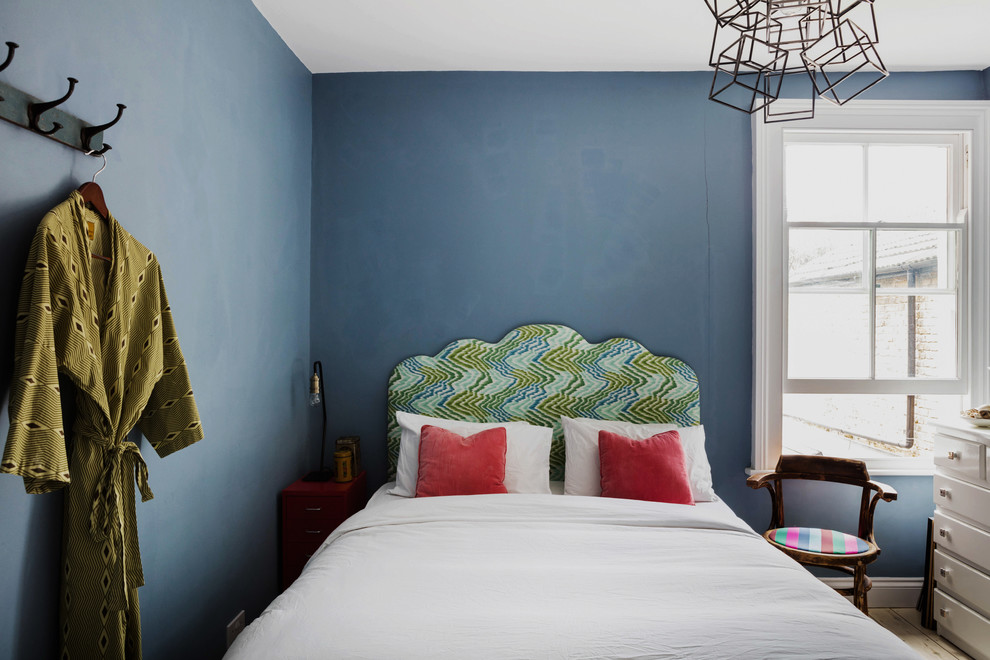 Inspiration pour une chambre d'amis bohème de taille moyenne avec un mur bleu, parquet clair, une cheminée standard et un manteau de cheminée en bois.