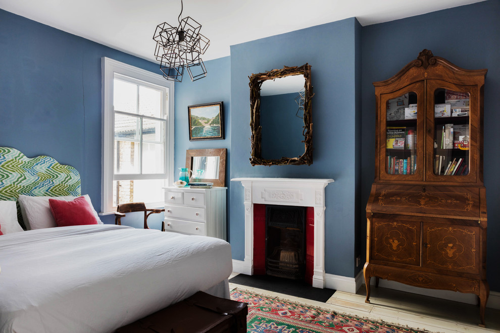 Idée de décoration pour une chambre d'amis tradition de taille moyenne avec un mur bleu, parquet clair, une cheminée standard et un manteau de cheminée en bois.