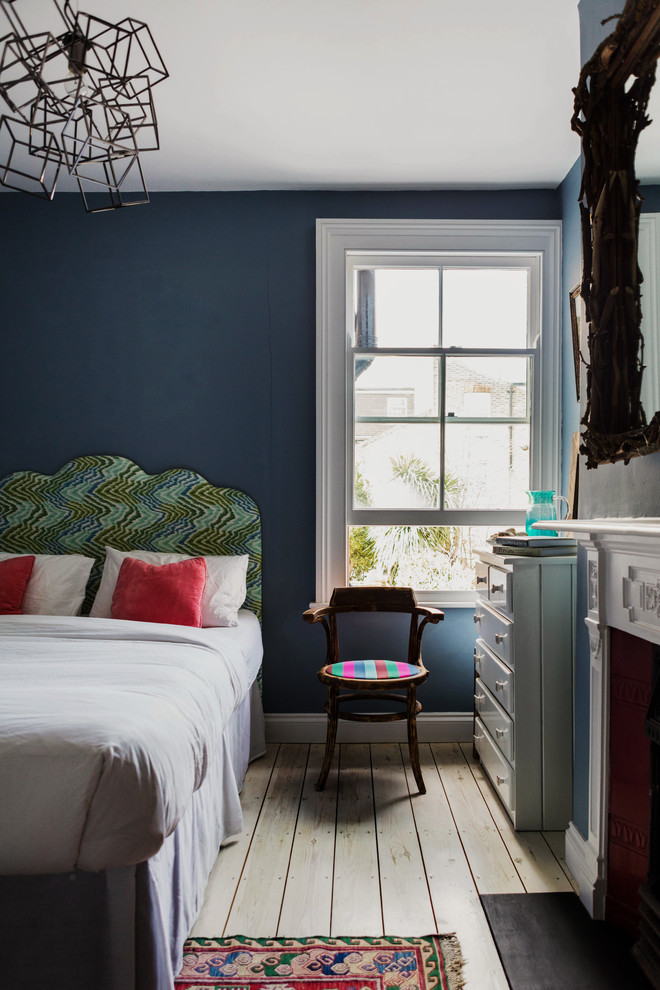 Пример оригинального дизайна: гостевая спальня среднего размера, (комната для гостей) в стиле фьюжн с синими стенами, светлым паркетным полом, стандартным камином и фасадом камина из дерева