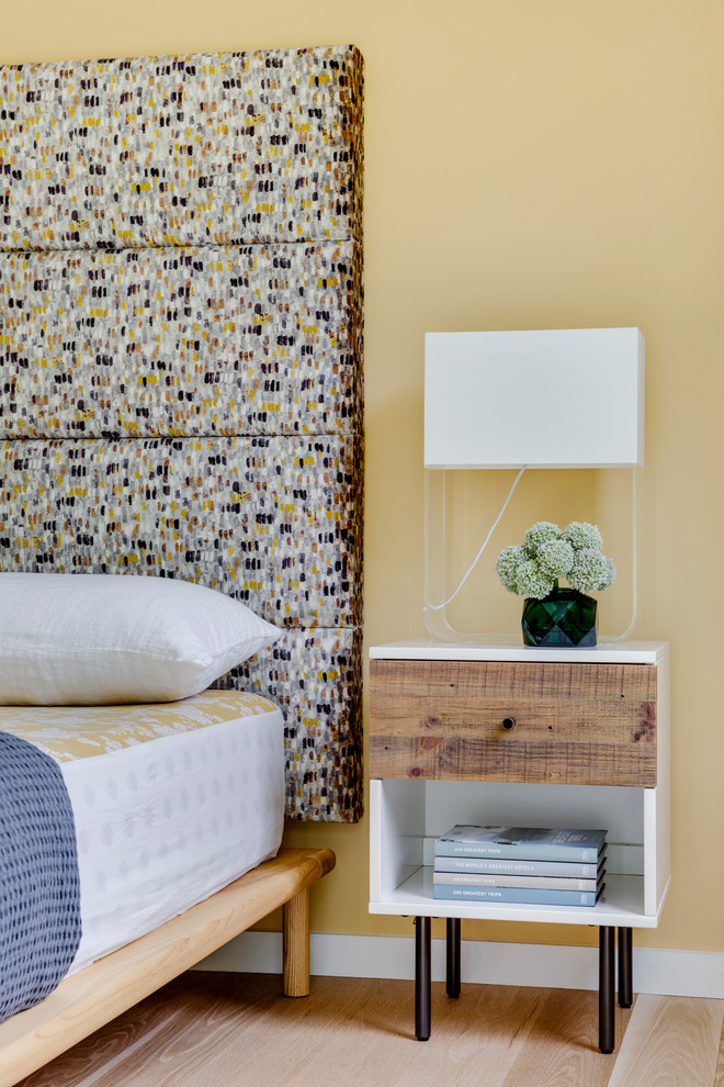 Imagen de habitación de invitados actual de tamaño medio con paredes amarillas y suelo de madera clara