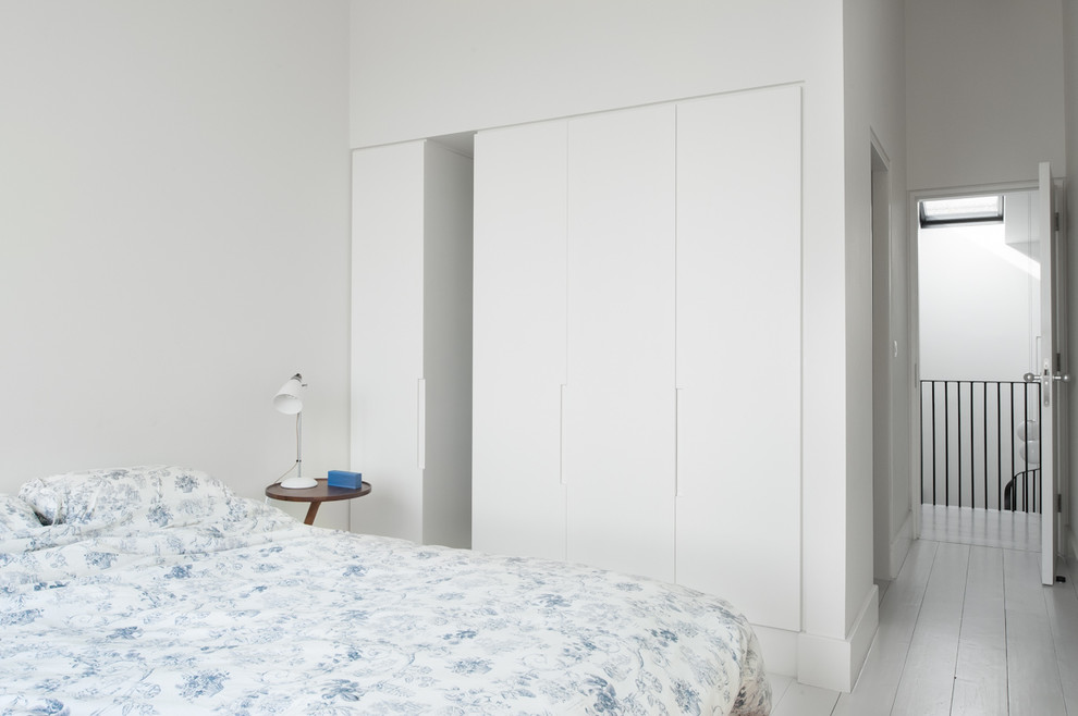Imagen de habitación de invitados clásica renovada de tamaño medio sin chimenea con paredes blancas y suelo de madera pintada