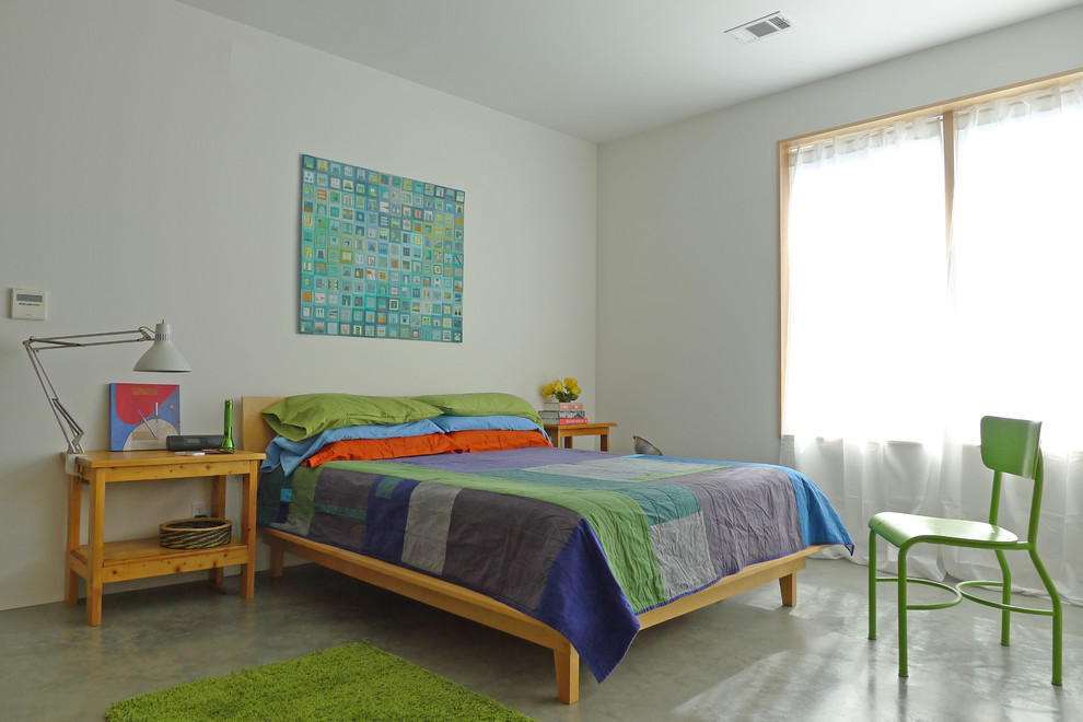 Immagine di una camera da letto contemporanea con pavimento in cemento e pareti bianche